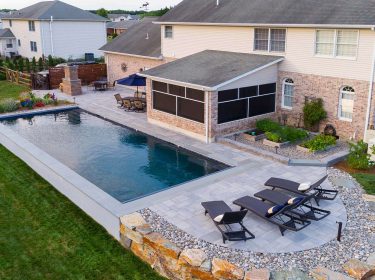 An in-ground pool surrounded by a hardscaped patio with lounge chairs