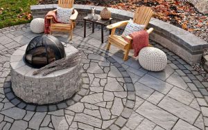 An overhead view of a hardscape patio with a firepit, table and chairs